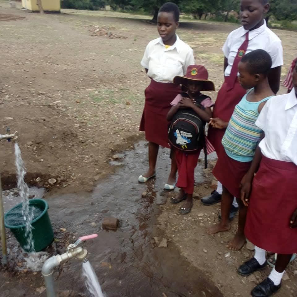 Girl students watching clean water flow from the solar-powered tap at school