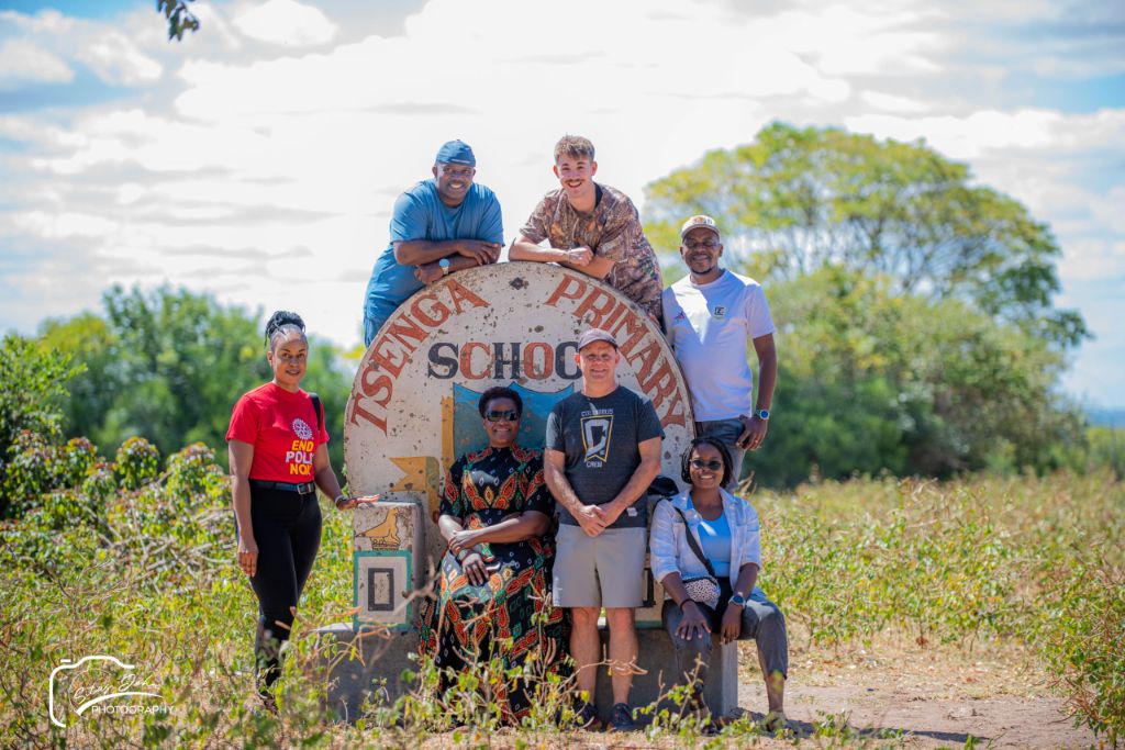 The team posing at the Tsenga Primary School entrance sign